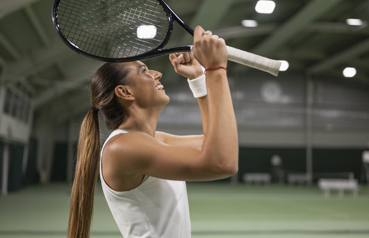 Excited female tennis player holding fists in winning gesture. Sport and healthy lifestyle concept.